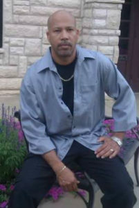 A man sitting on top of a bench in front of flowers.