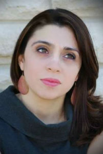 A woman with long dark hair wearing large earrings.