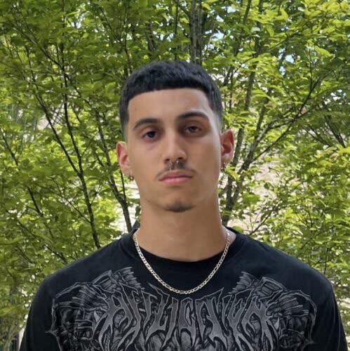 Young man standing outdoors in graphic tee.